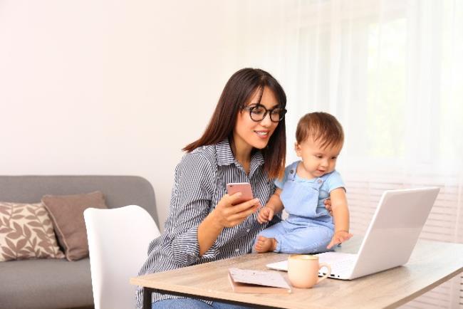 אישה יושבת ועובדת מול מחשב עם הילד שלה במסגרת הסגר עקב מגפת הקורונה